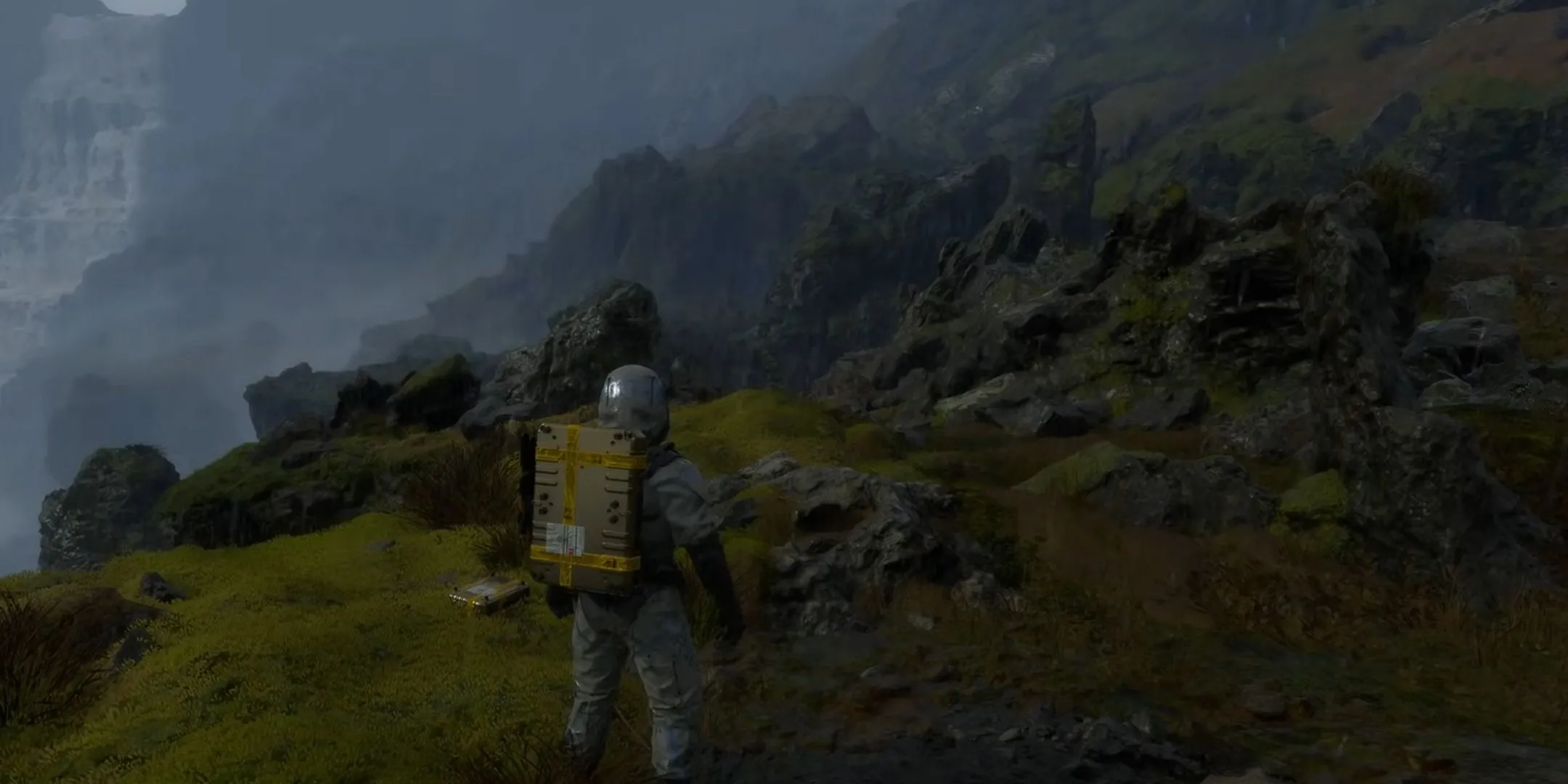 Sam Porter Bridges cẩn trọng vượt qua địa hình hiểm trở, quản lý hàng hóa trên lưng trong game Death Stranding