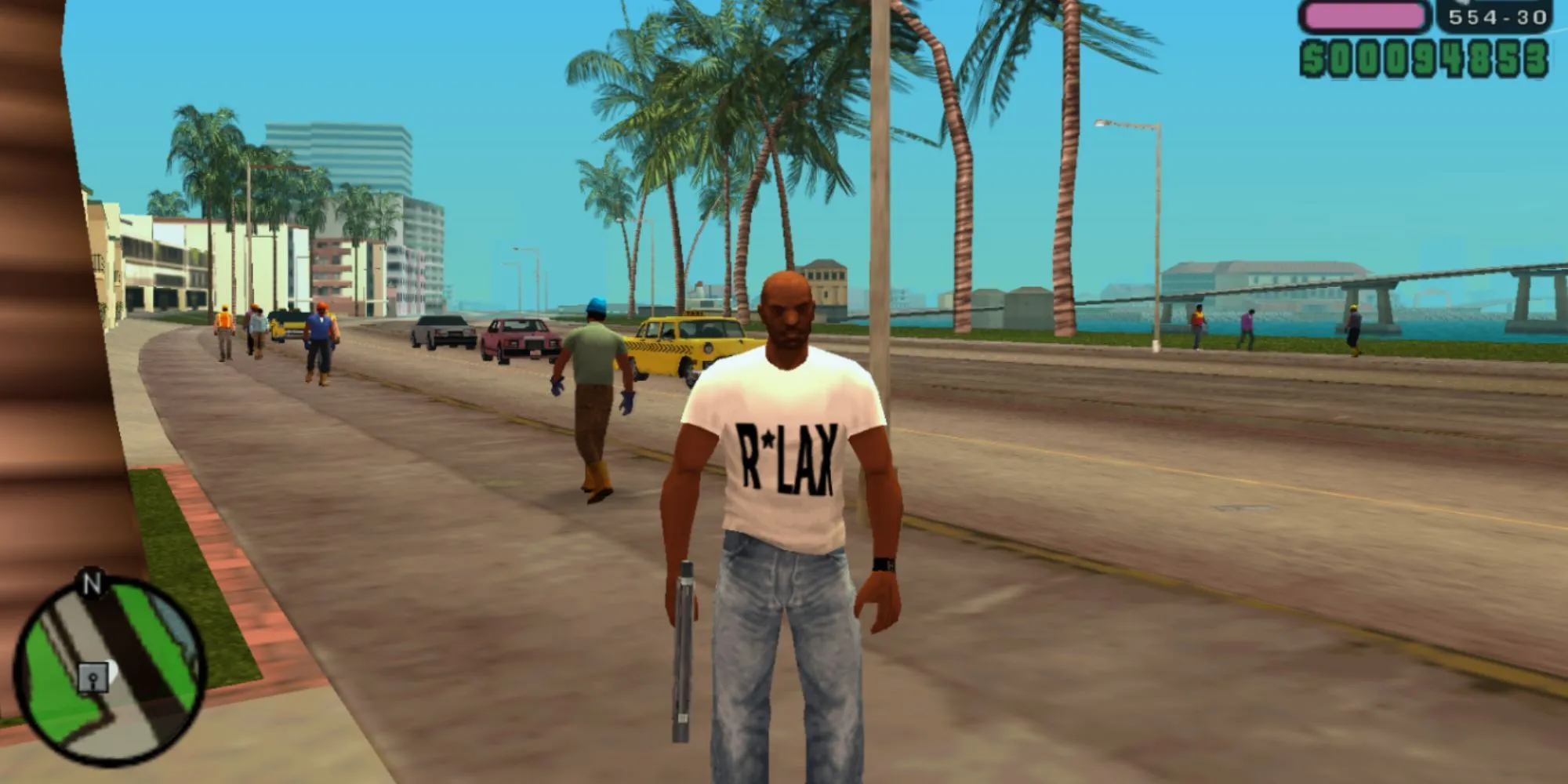 Victor Vance đứng trên con đường ven biển cầm súng trong GTA Vice City Stories
